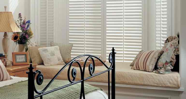 Polywood shutters in a modern bedroom bay window.